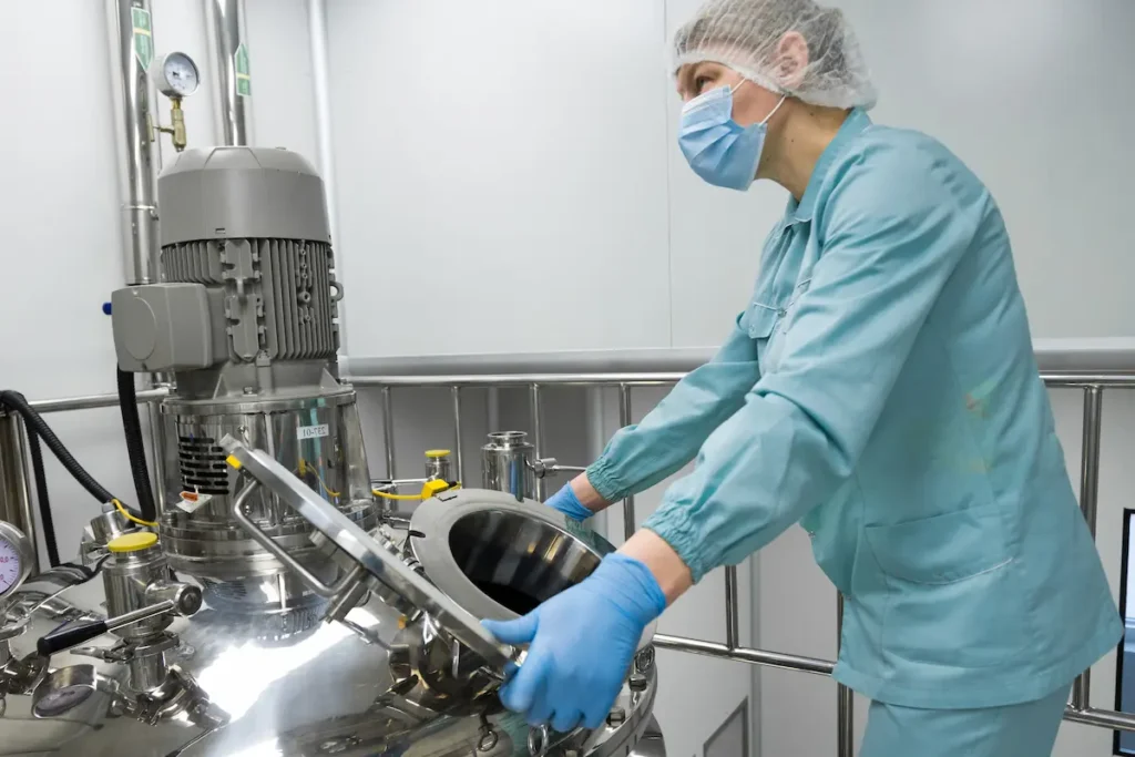 Bomba centrífuga sanitaria instalada en una planta farmacéutica, con un trabajador asegurando el cumplimiento de las normativas de higiene y seguridad en el proceso de producción.